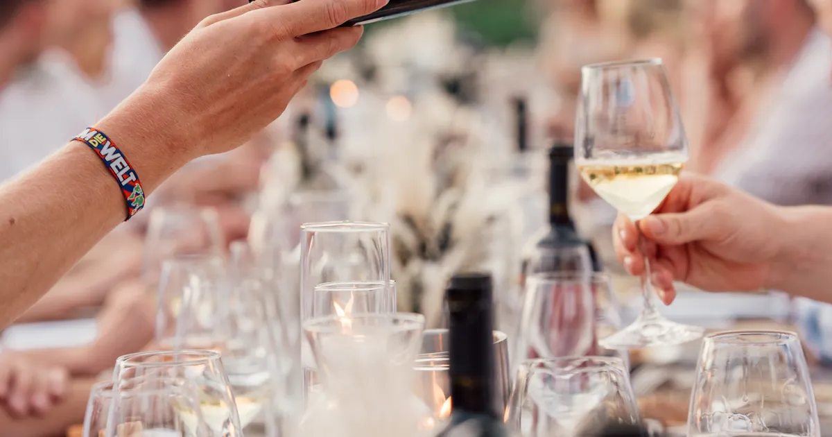 Invité servant du vin à ses voisins lors d'un dîner de mariage en extérieur